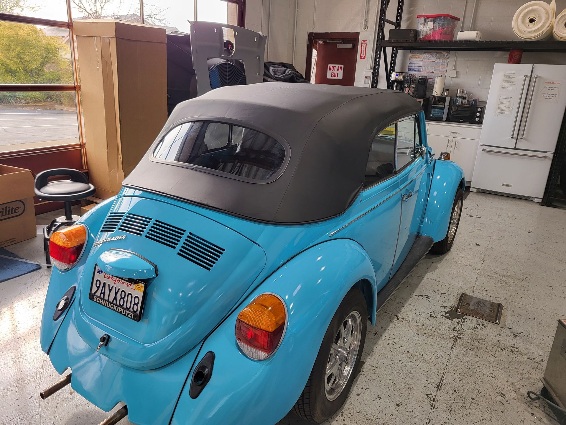 A blue car with a black top is parked in a garage.