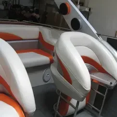 The inside of a boat with orange and white seats and a table.