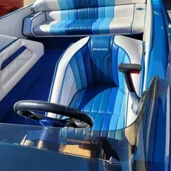 A blue boat with blue and white seats and a steering wheel
