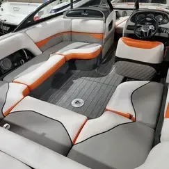 The inside of a boat with gray and orange seats and a steering wheel.