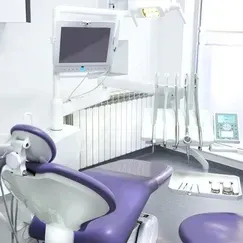 There is a purple dental chair in the dental office.