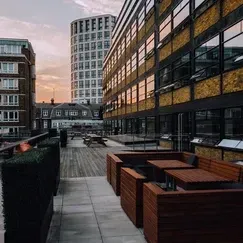 A rooftop terrace with tables and chairs in front of a building.