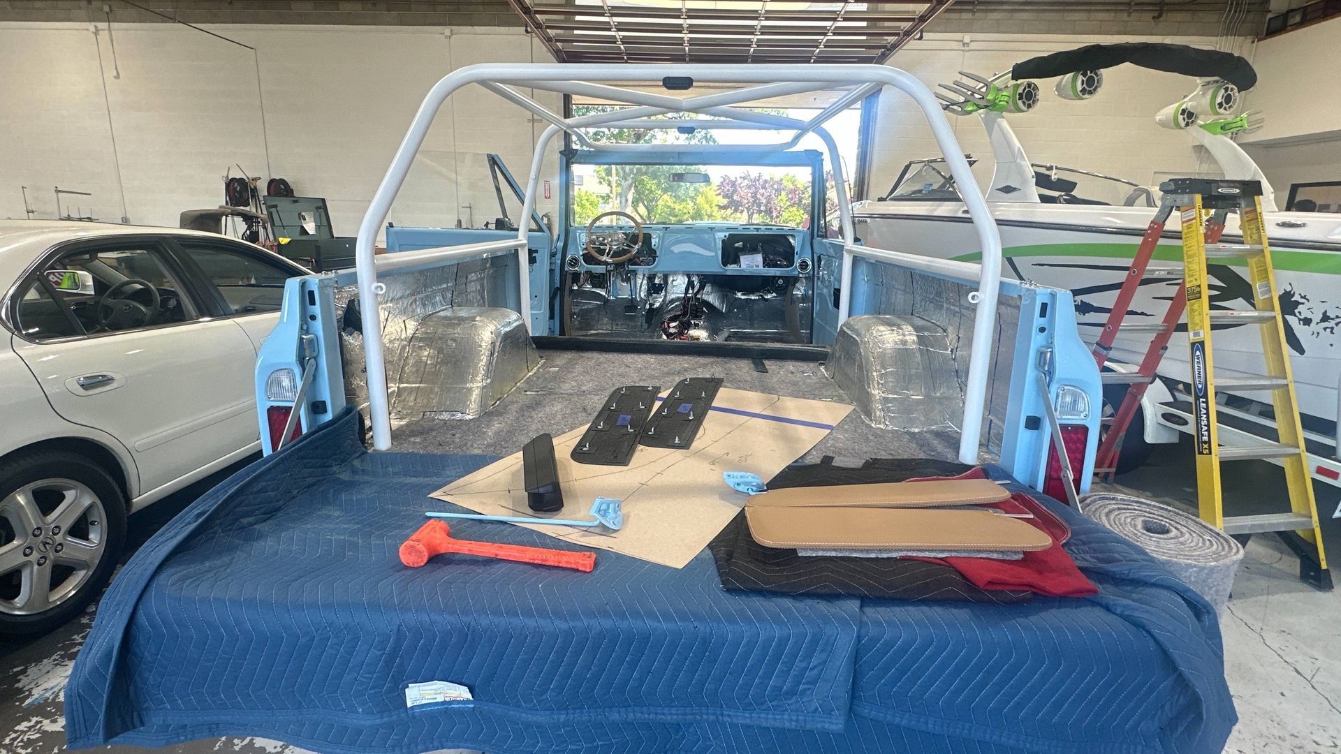 Light blue truck bed with roll cage, interior parts laid out. Garage setting.