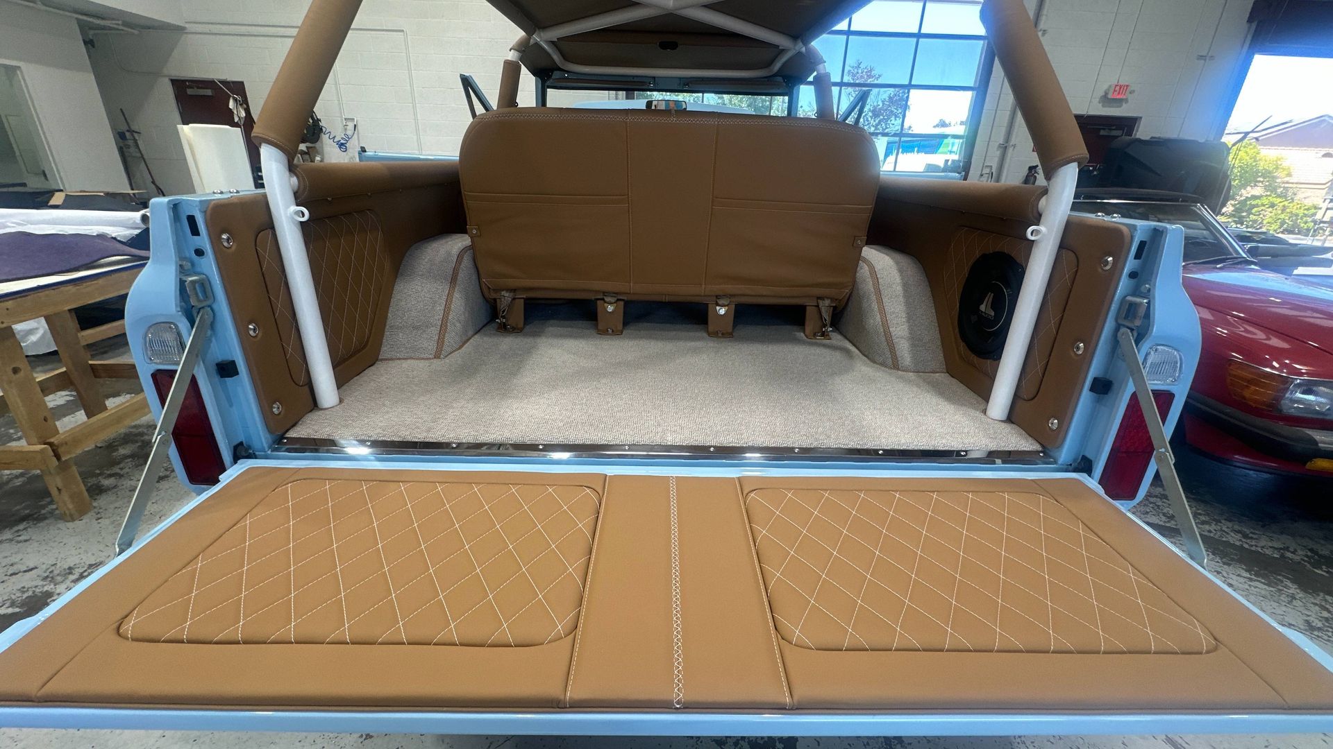 Open tailgate of a classic truck interior with tan upholstery, diamond stitching, and light blue trim.