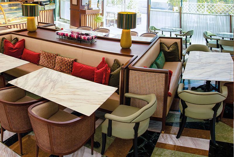 Restaurant interior with booth seating, marble-top tables, and various chairs.