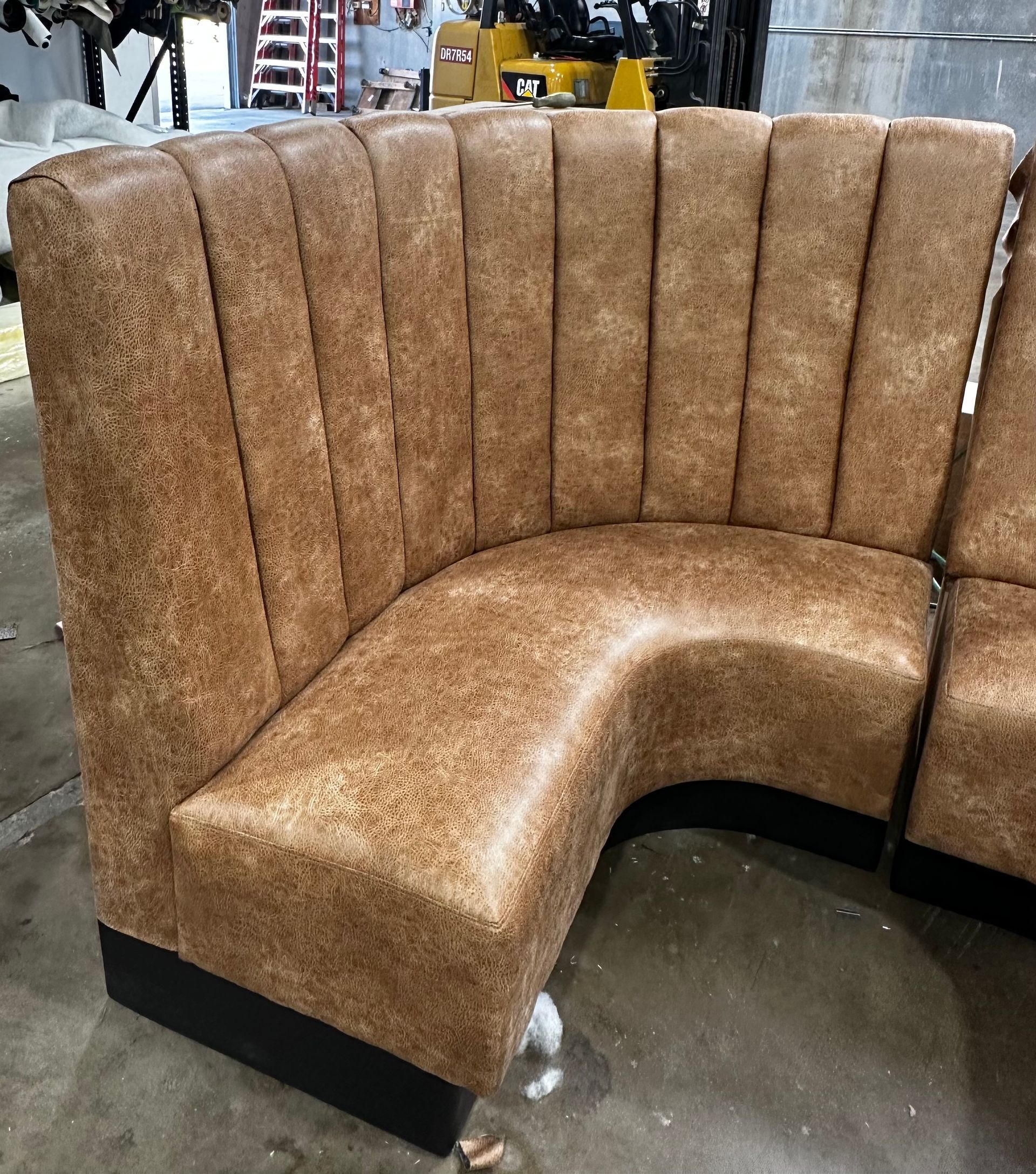 A brown couch is sitting on a concrete floor in a room.