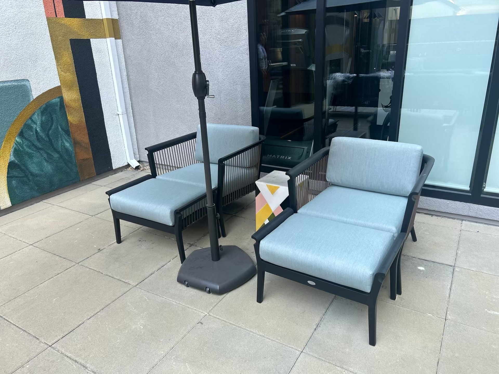 A patio with chairs and an umbrella in front of a building.