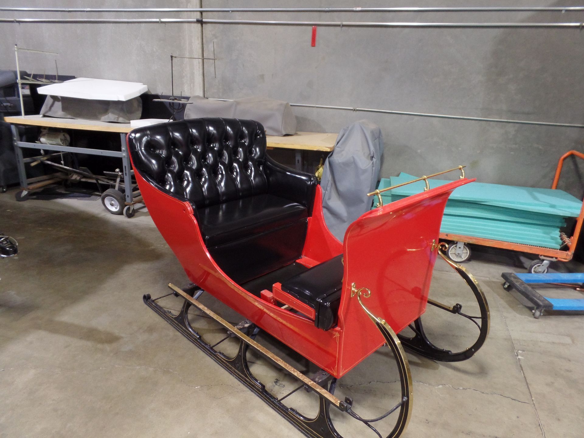 A red sleigh with black seats is in a garage