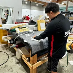 A man is working on a piece of fabric on a table in a factory.