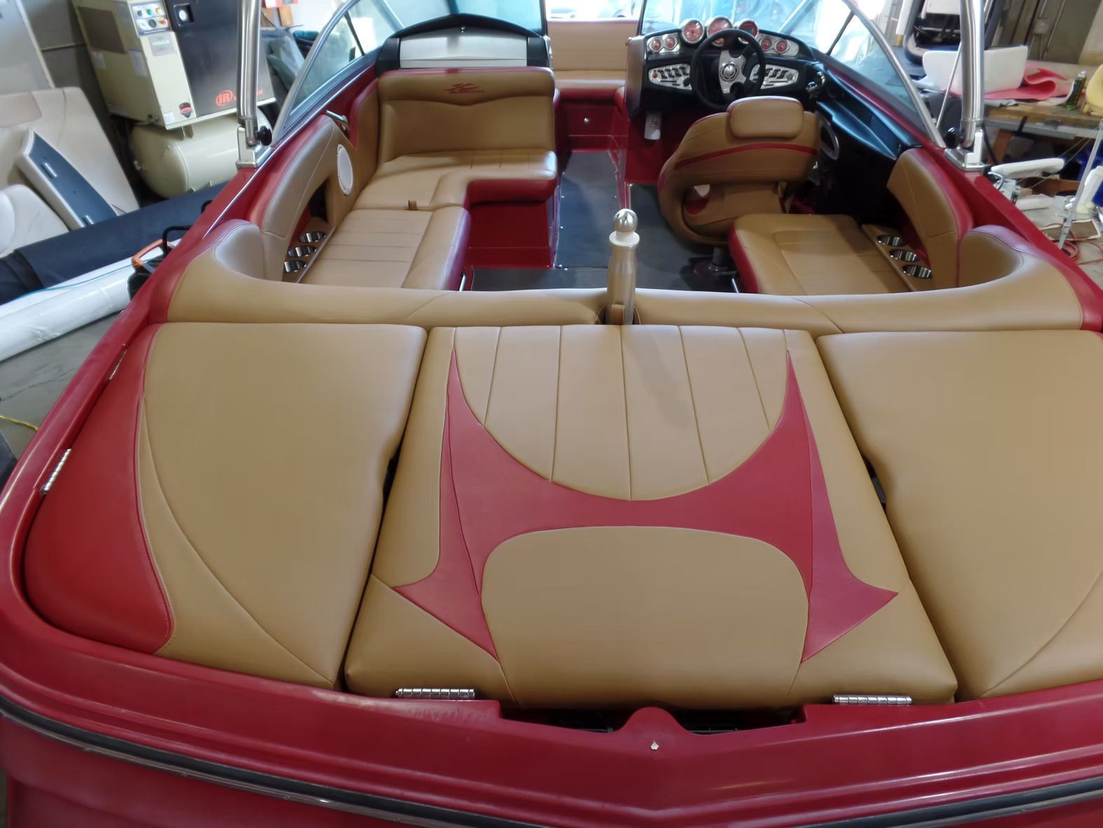 A red and tan boat is sitting in a garage