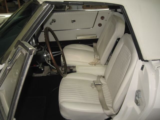 A white car with white seats and a wooden steering wheel
