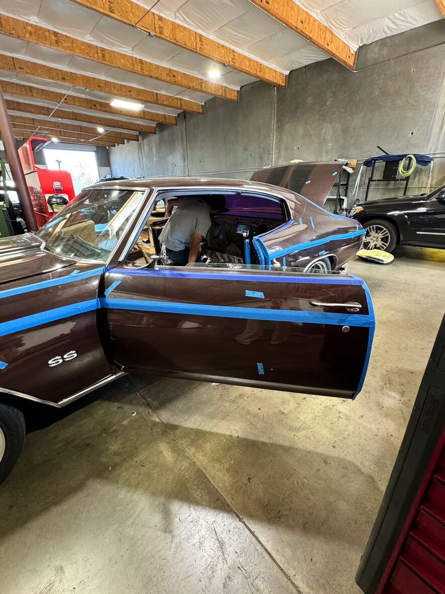 A man is working on a car in a garage with the door open.
