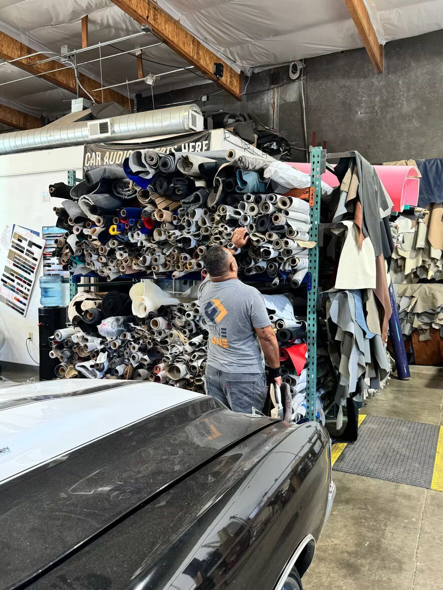 A man is standing in front of a pile of fabric in a garage.