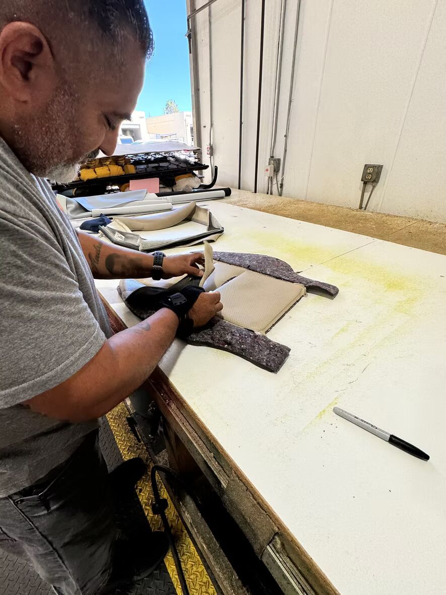 A man is sitting at a table working on a piece of fabric.