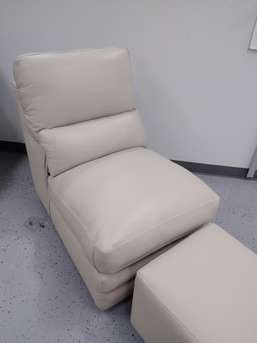 A chair and ottoman in a room with a white wall