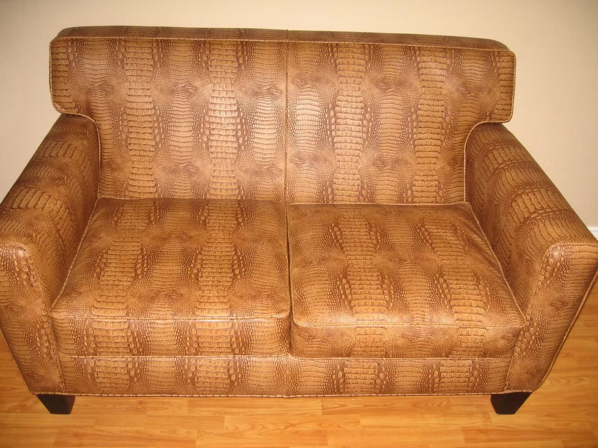 A brown leather couch is sitting on a wooden floor