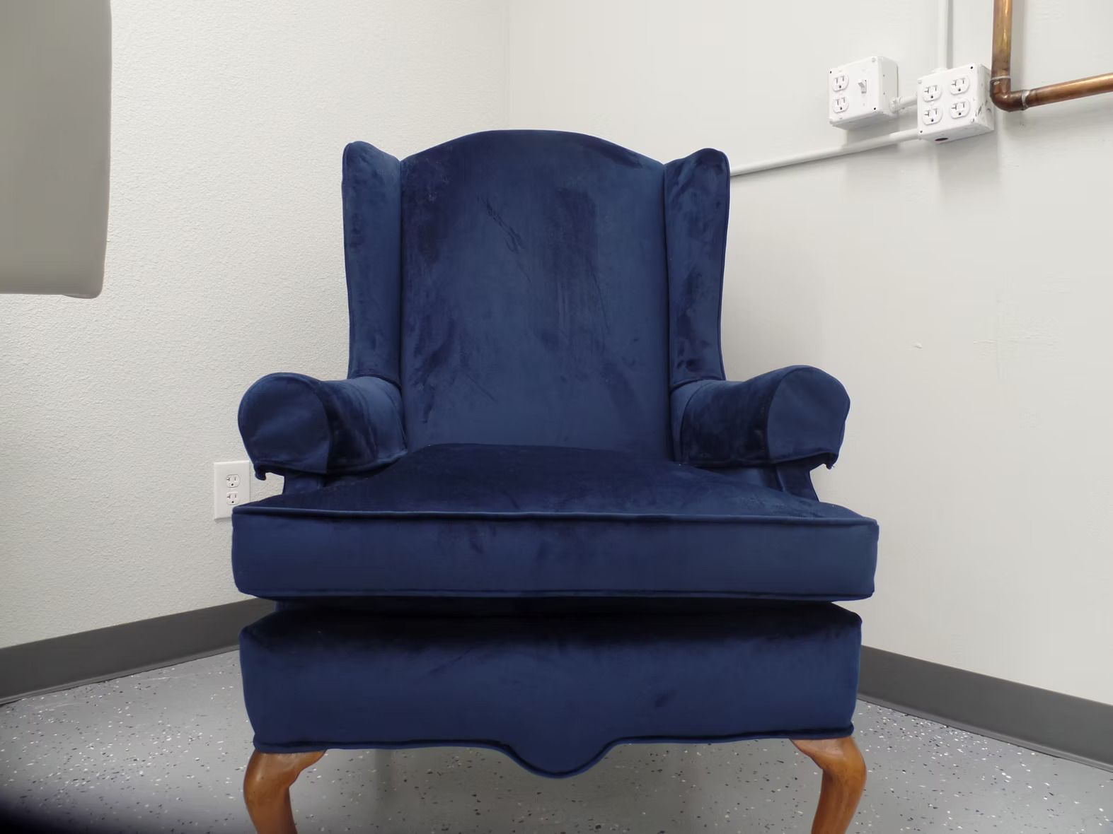 A blue chair is sitting in a corner of a room.