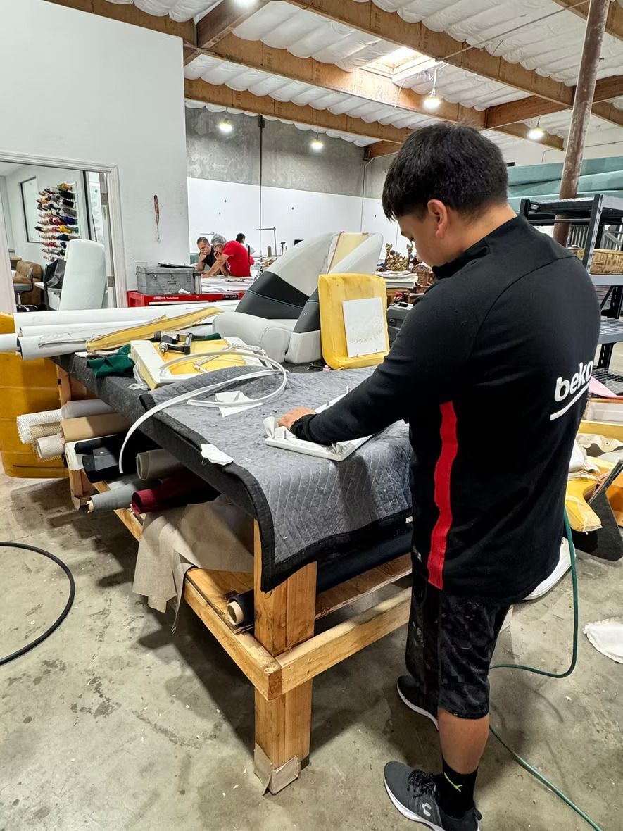 A man is working on a piece of fabric in a warehouse.