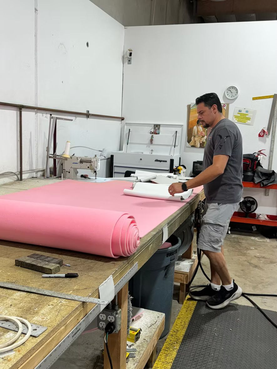 A man is working on a piece of pink fabric on a table.