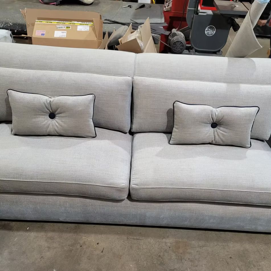 A grey couch with two pillows on it in a warehouse