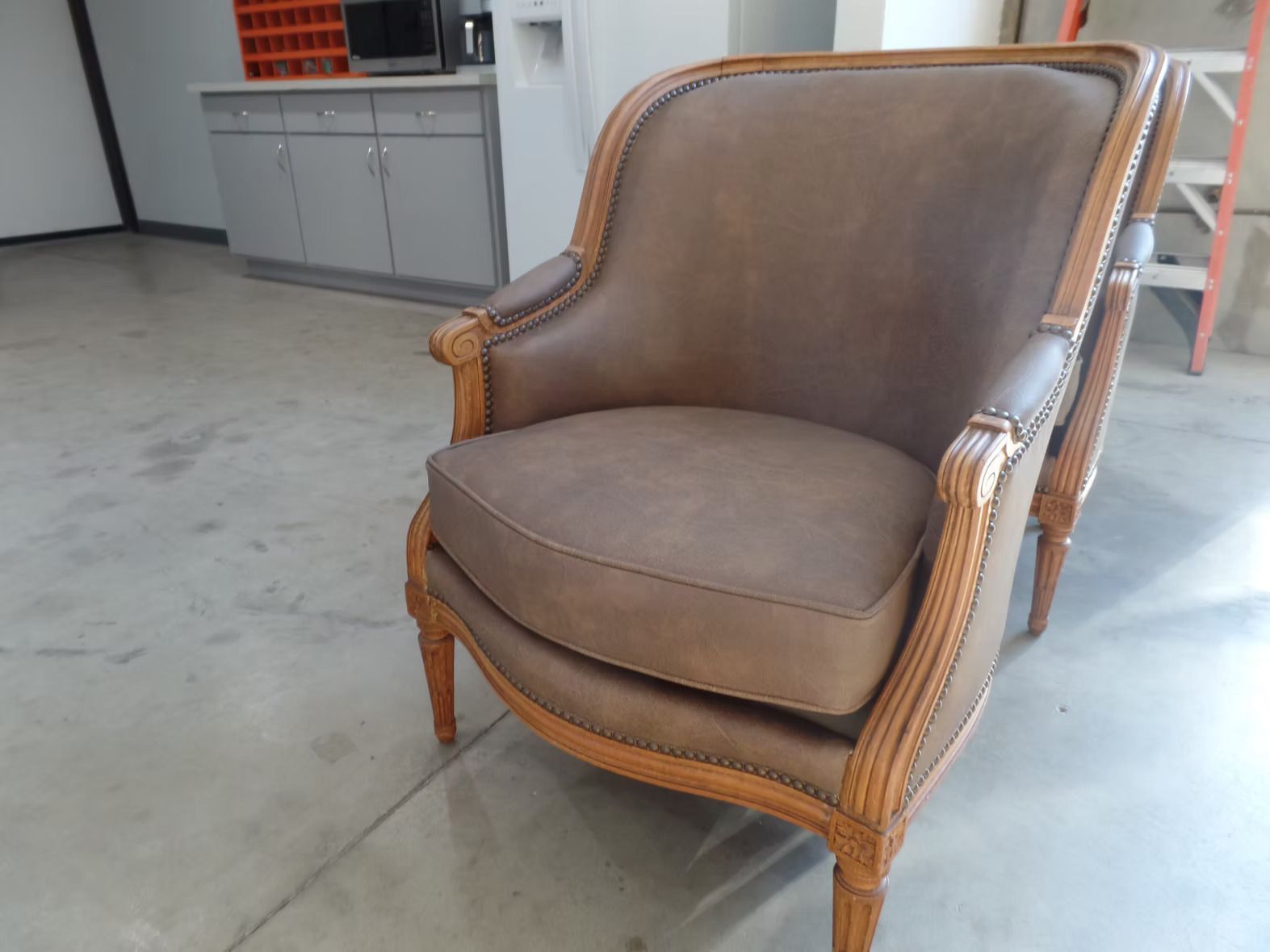 A brown leather chair is sitting on a concrete floor