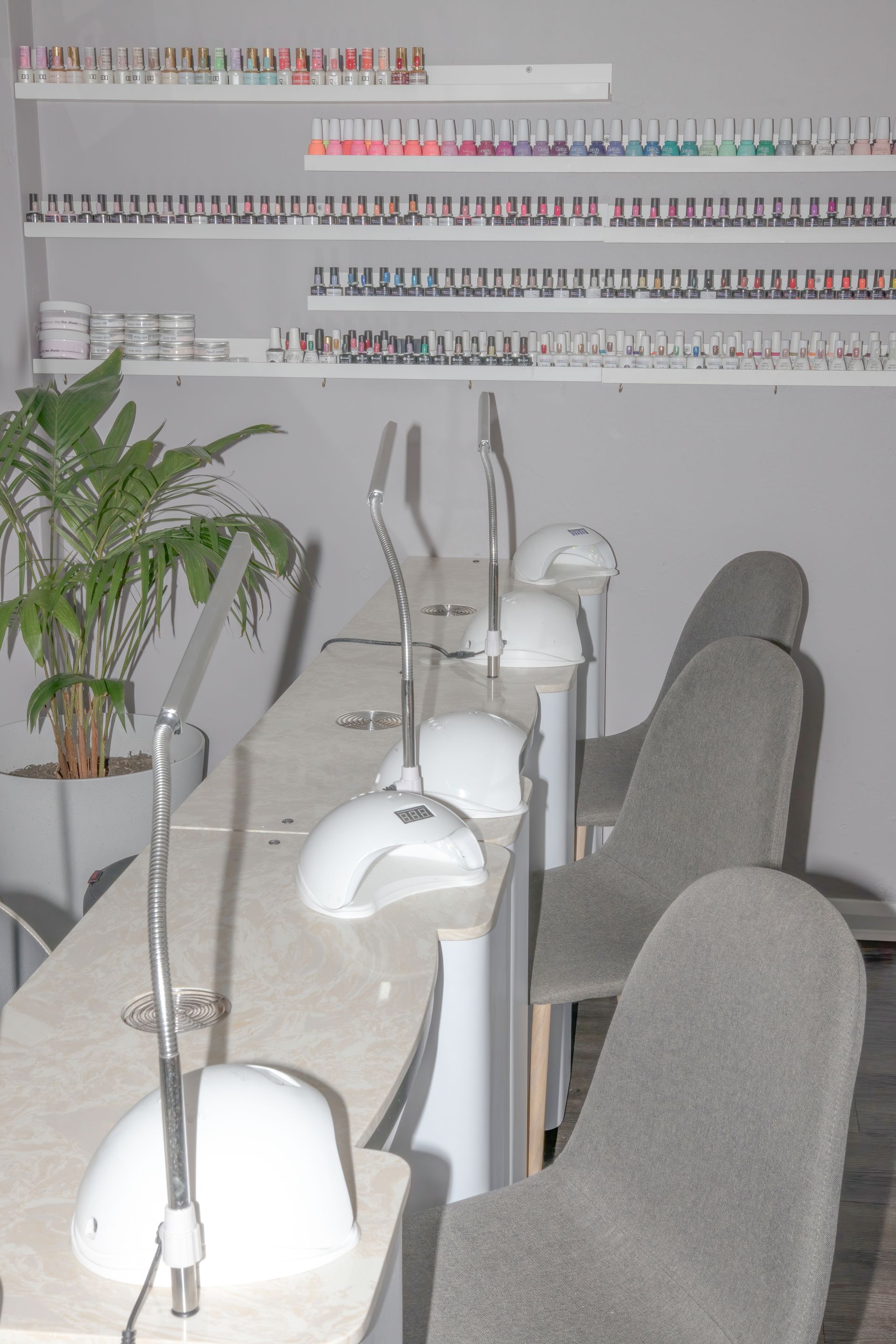 Nail salon interior with manicure stations, gray chairs, and shelves of nail polish. — Admire Skincare and Beauty in Taree, NSW