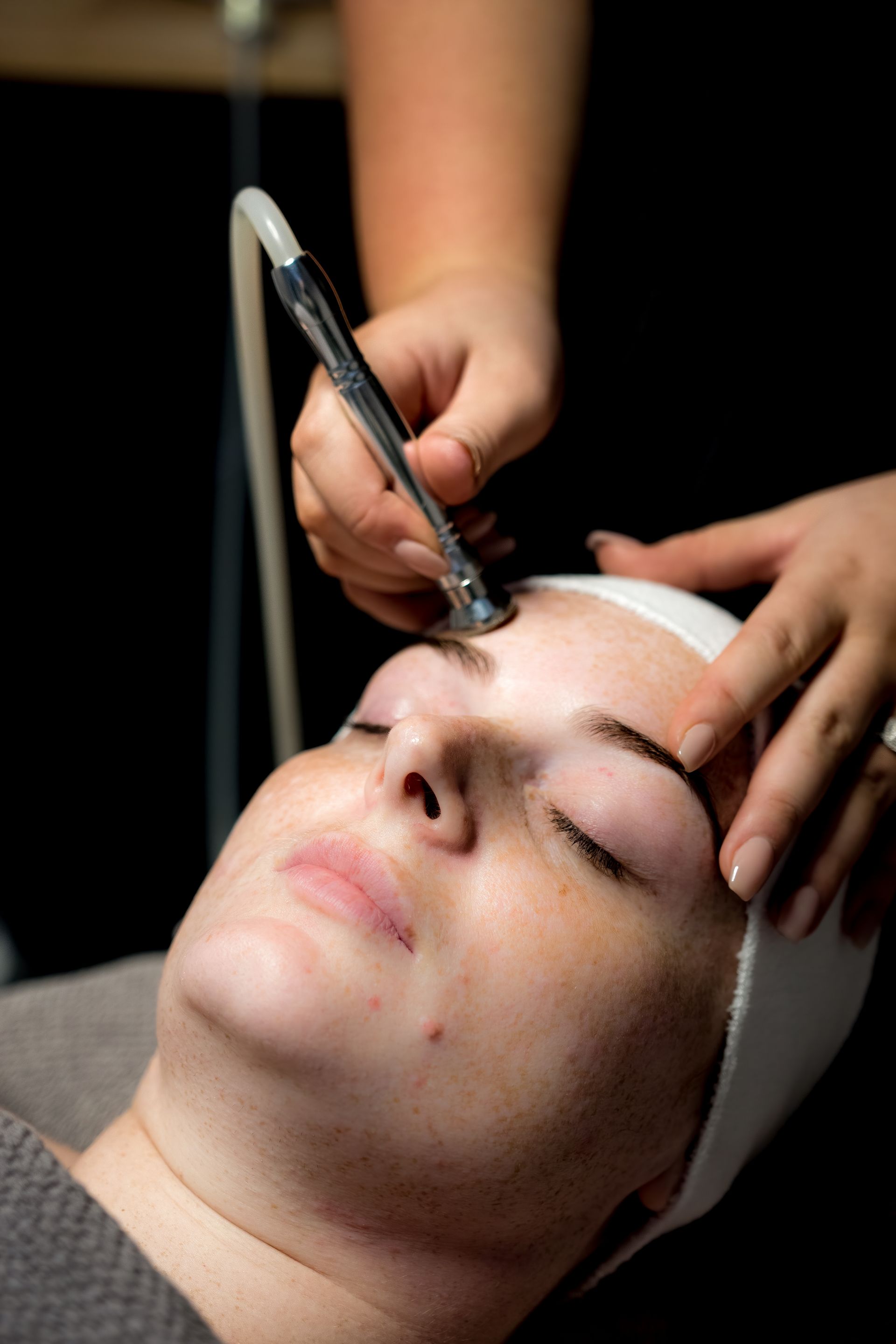Woman Receiving a Facial Treatment With a Handheld Device, Lying on a Table — Admire Skincare and Beauty in Taree, NSW