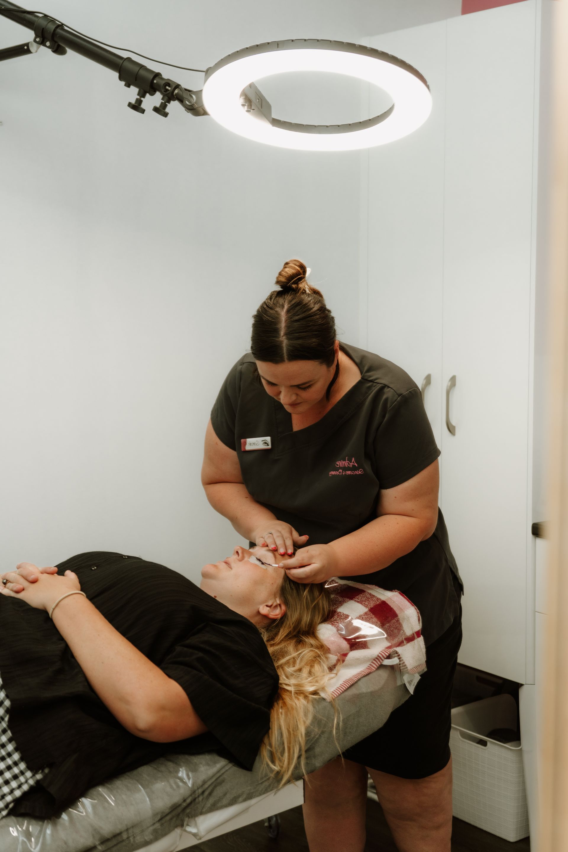 Woman performing beauty treatment on client under a ring light in a salon. — Admire Skincare and Beauty in Taree, NSW
