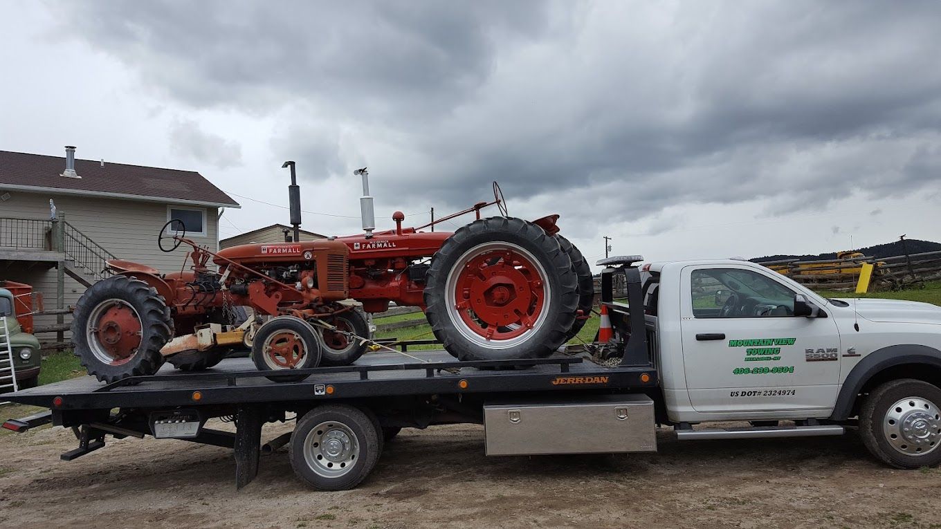 Red car being loaded onto a tow truck at sunset.
