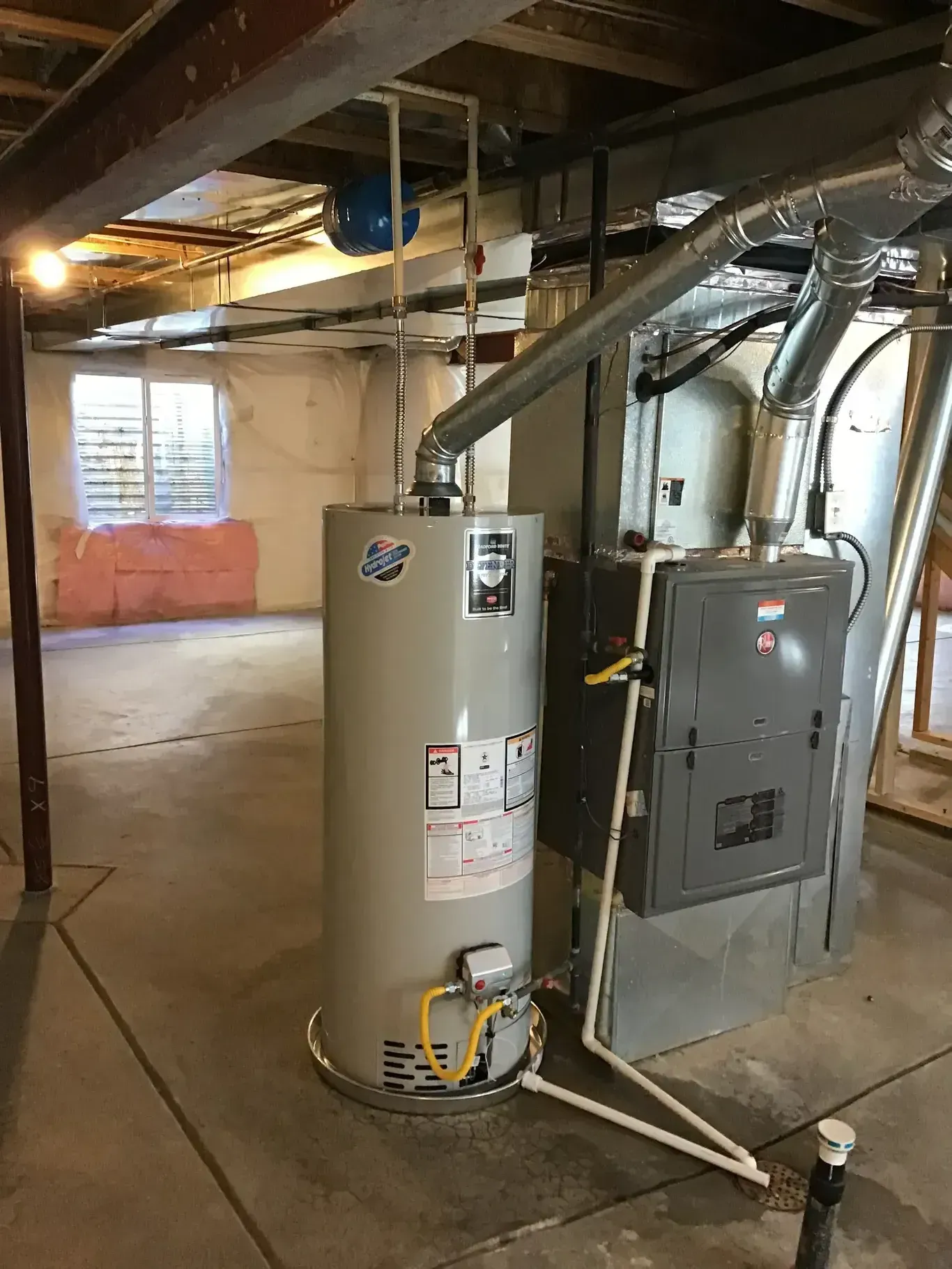 Basement with a water heater, furnace, and electrical panel; window in the background.