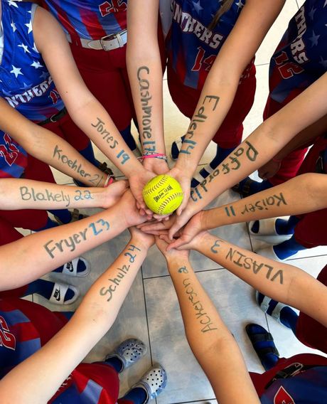 A group of children are holding hands in a circle with their names written on their arms