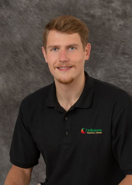 A young man wearing a black polo shirt is smiling for the camera.