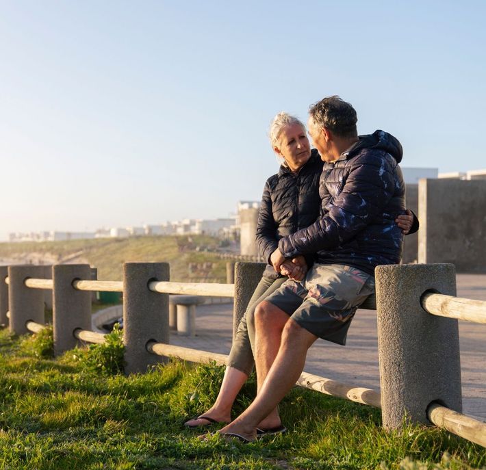 A man and a woman are sitting next to each other on a fence post