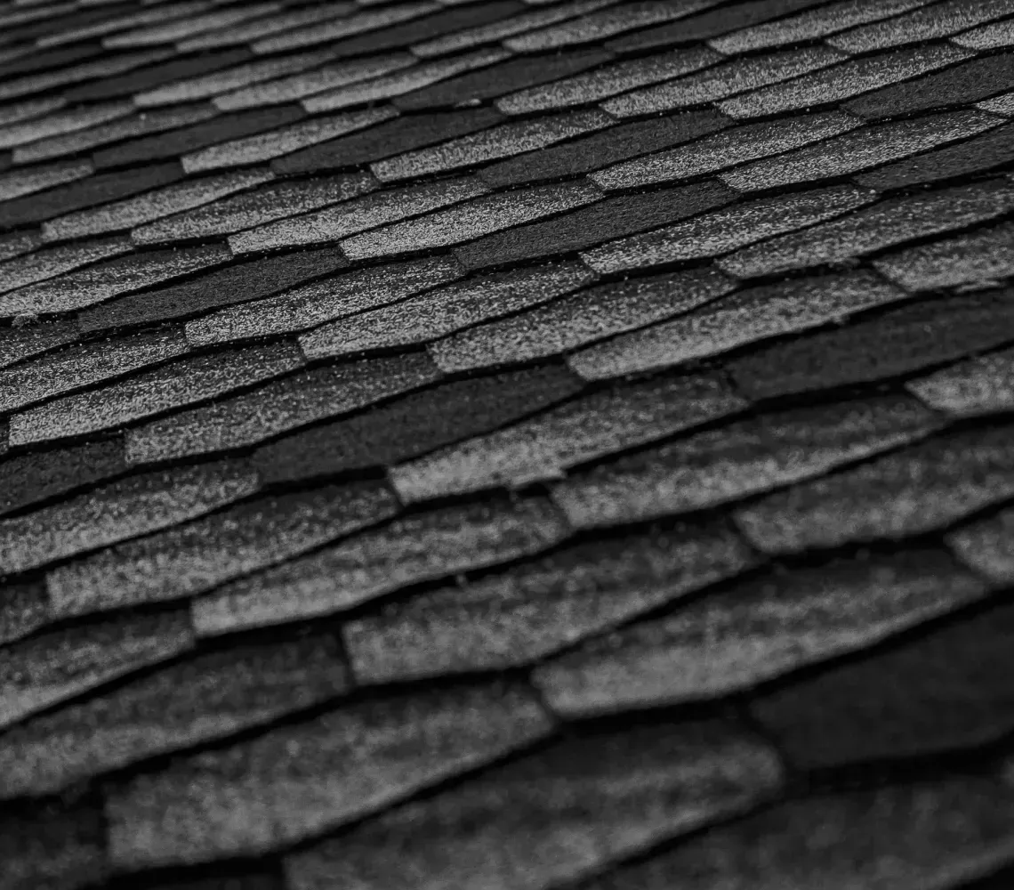 Close-up of dark asphalt shingles with a textured, overlapping pattern