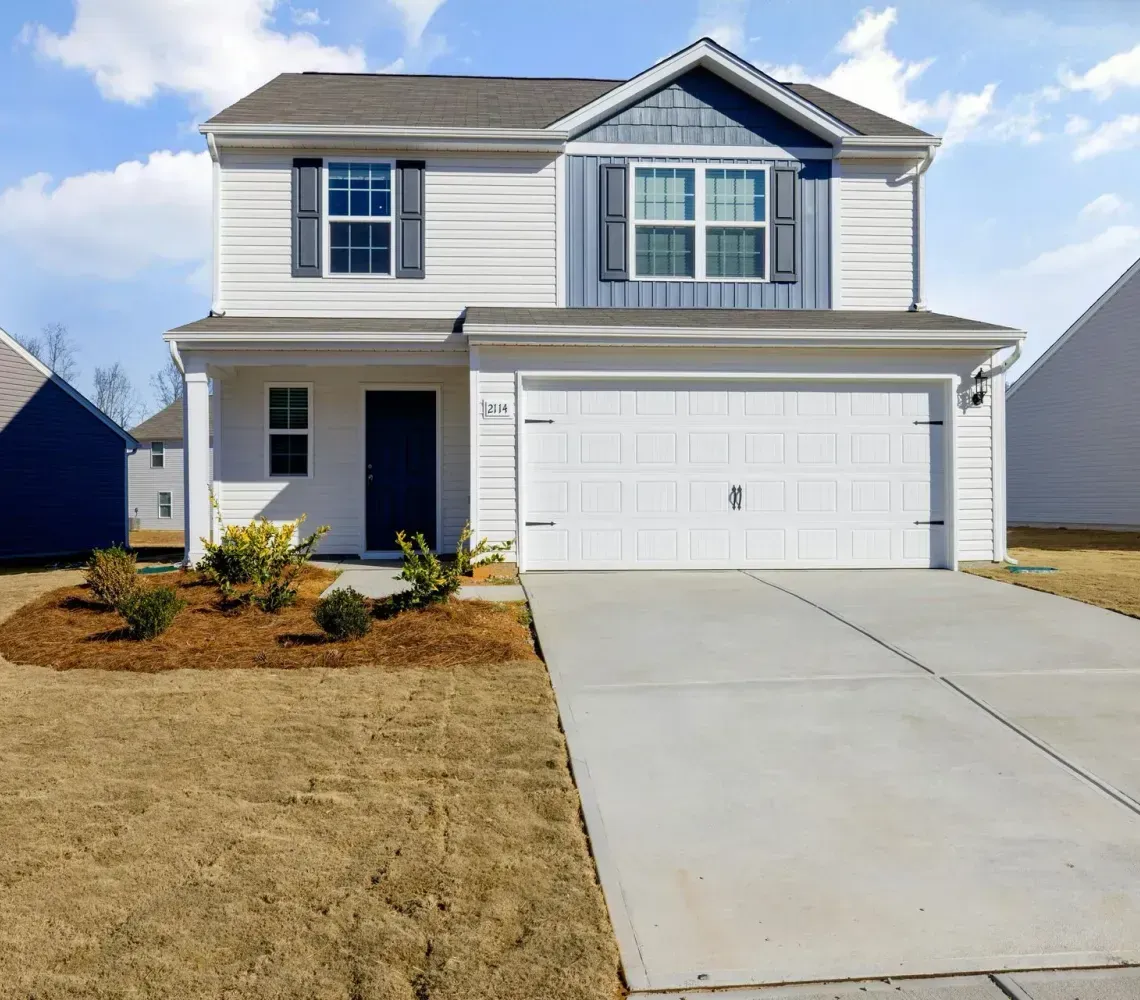 Two-story suburban house with white garage, front lawn, and driveway under a clear sky