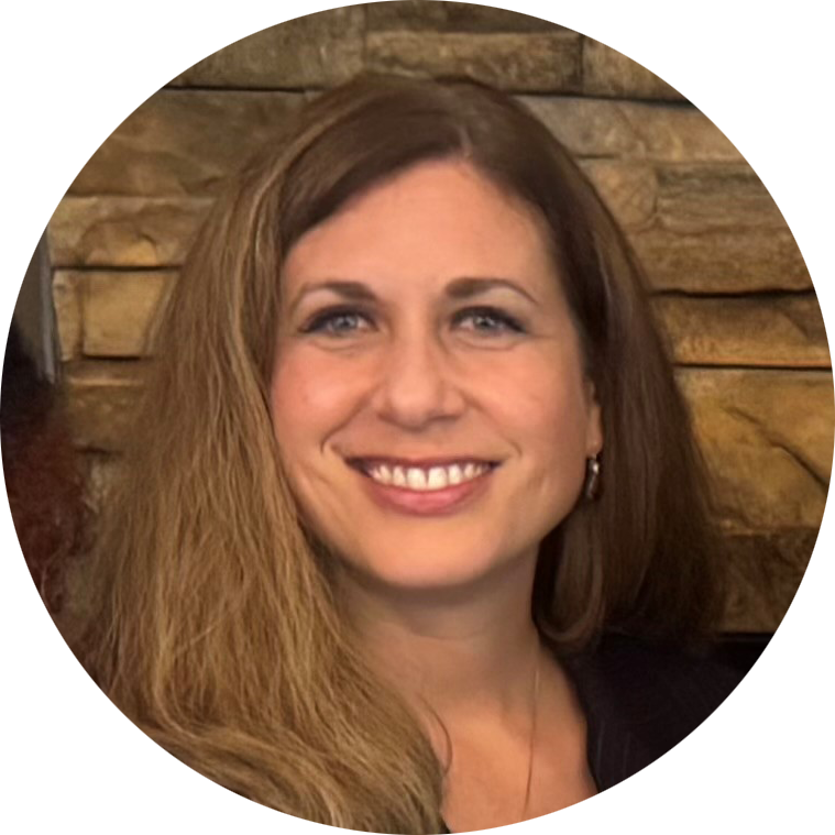 A woman wearing a white shirt and earrings is smiling in front of a window.