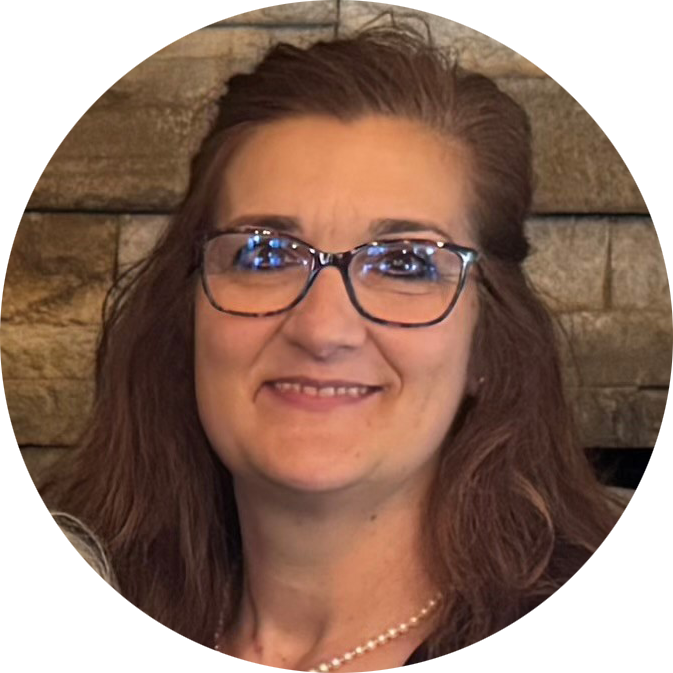 A woman wearing a white shirt and earrings is smiling in front of a window.