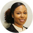 A woman wearing a white shirt and earrings is smiling in front of a window.
