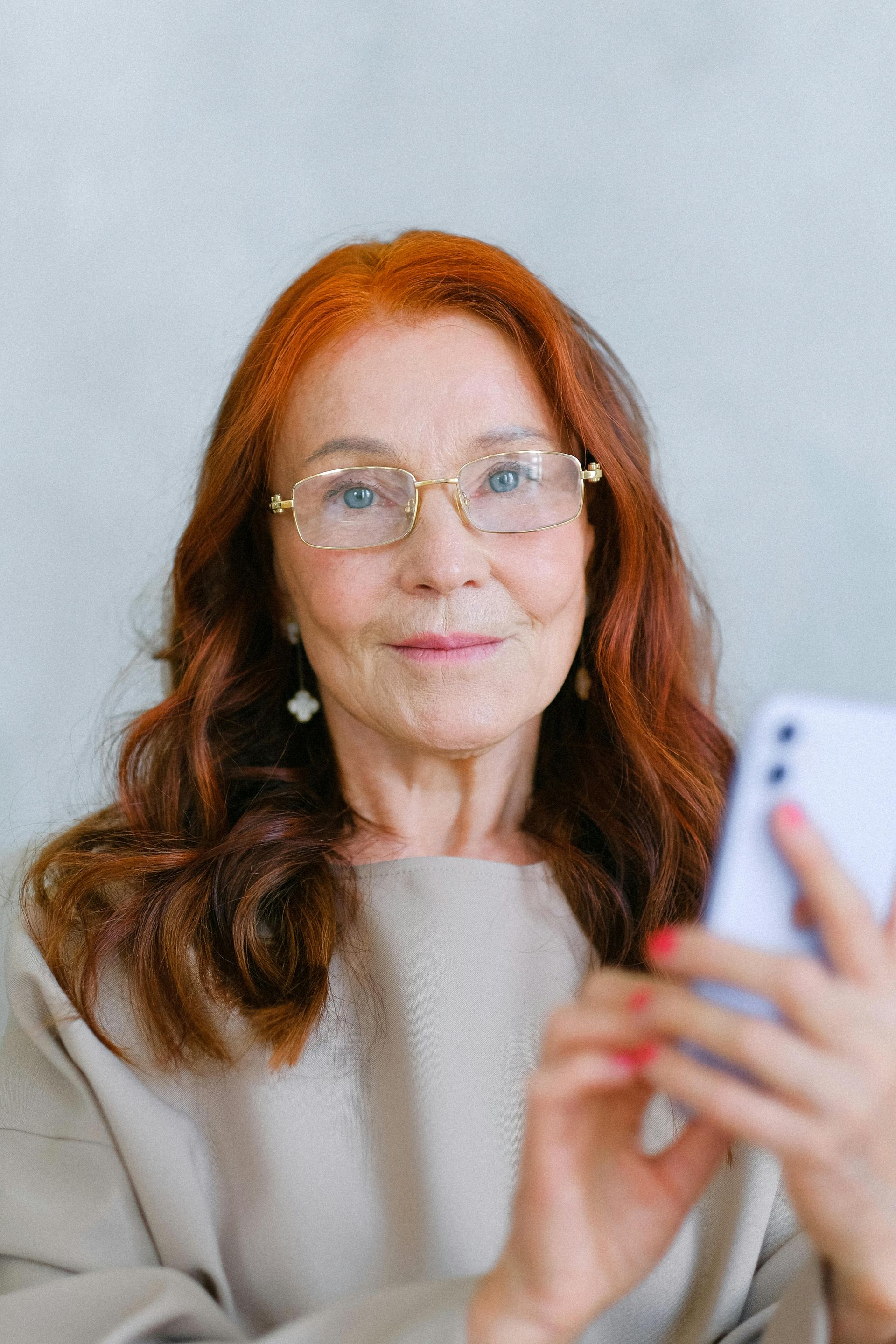 An older woman wearing glasses and a purple shirt is knitting.