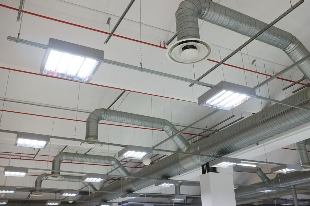 White ceiling with ventilation ducts, lights, and red pipes.