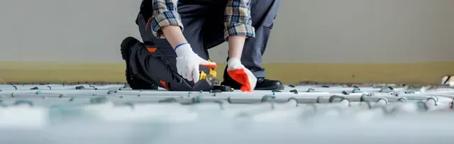 A man is kneeling down on the floor using a measuring tape.