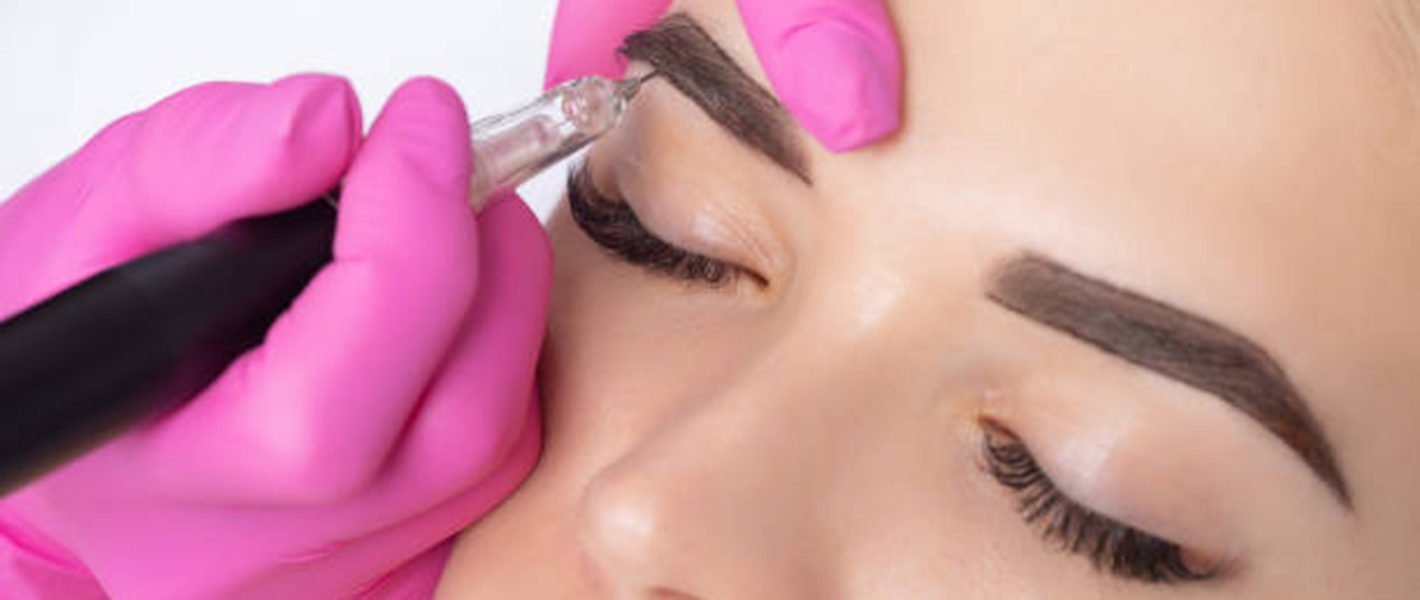 Una mujer se está tatuando las cejas con una máquina.