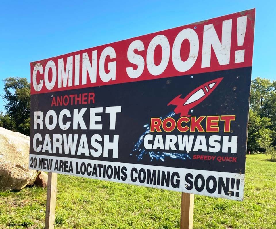 A sign that says coming soon another rocket carwash