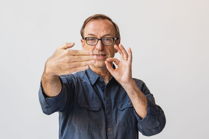 Jerry Michalski wearing glasses is making an ok sign with his hands.