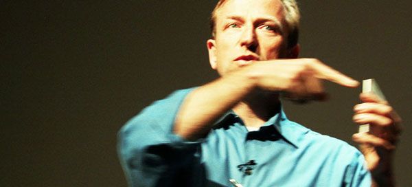Jerry Michalski in a blue shirt is holding a microphone and pointing