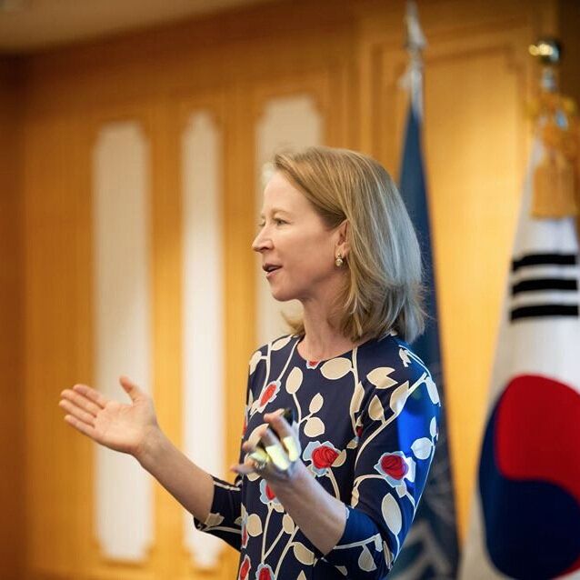 April Rinne in a blue dress stands in front of a korean flag