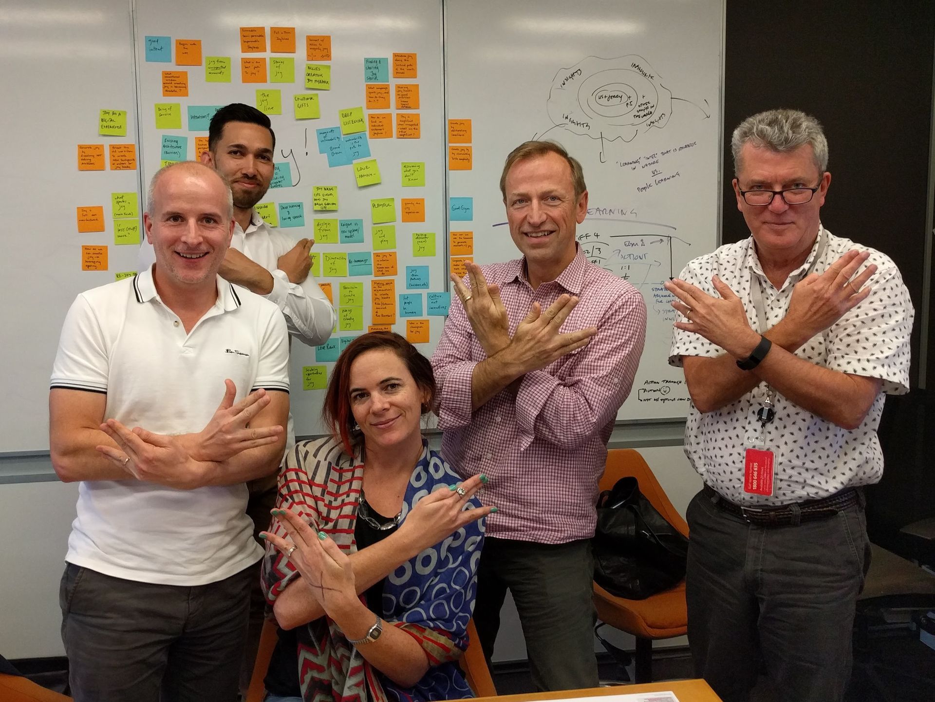 A group of people including Jerry Michalski standing in front of a white board with sticky notes on it