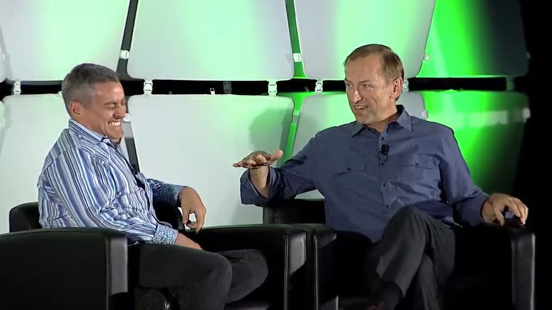 Jerry Michalski and another man are sitting in chairs talking to each other on a stage.
