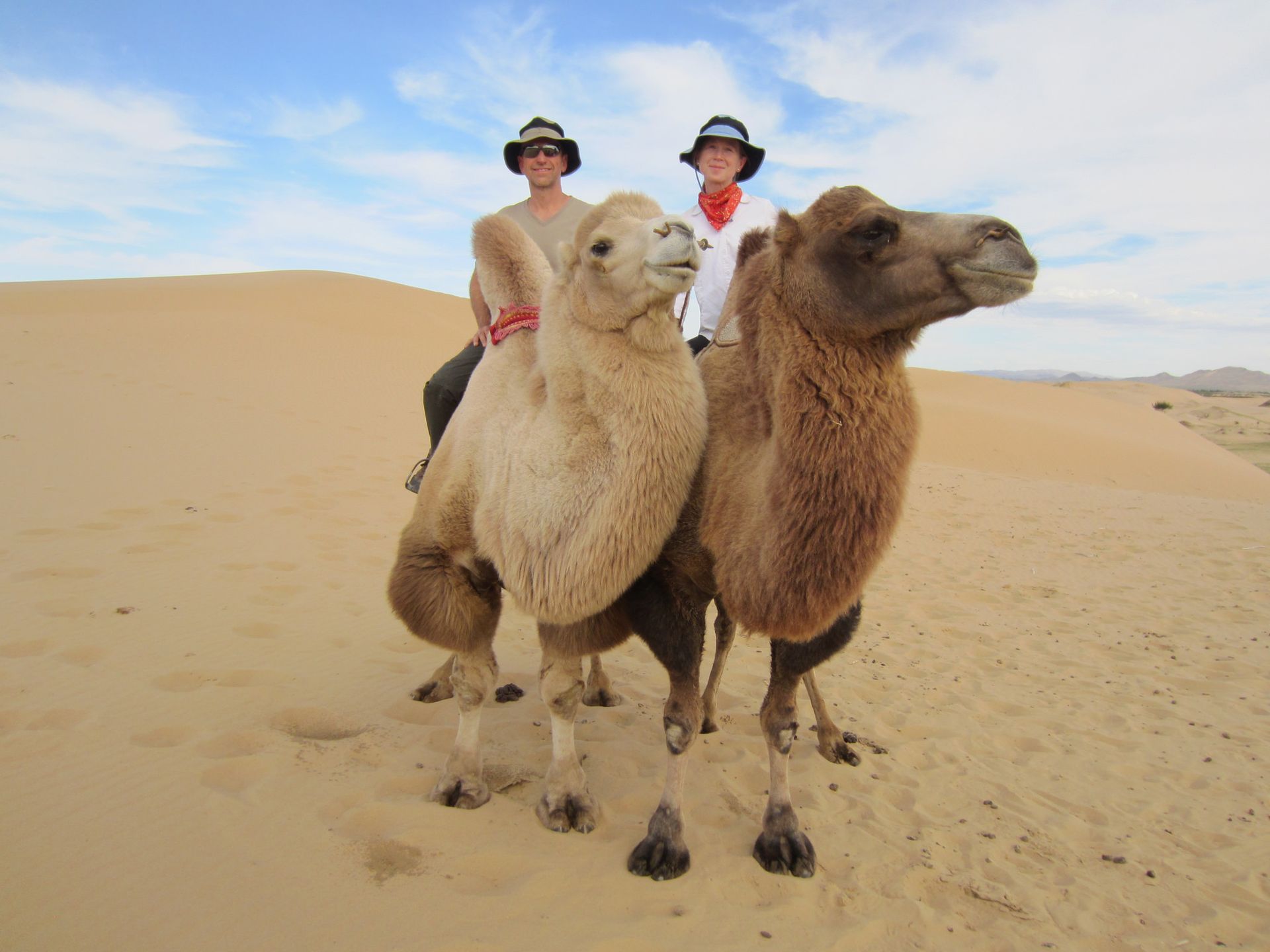Jerry Michalski and April Rinne are riding camels in the desert