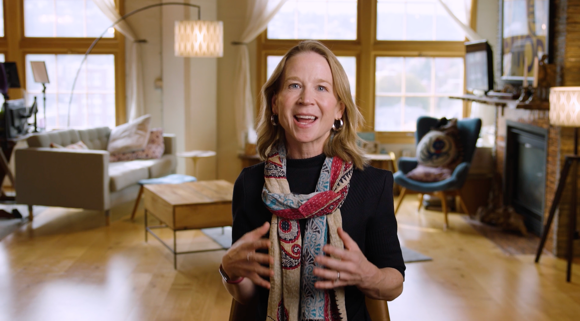 April Rinne wearing a scarf is standing in a living room.